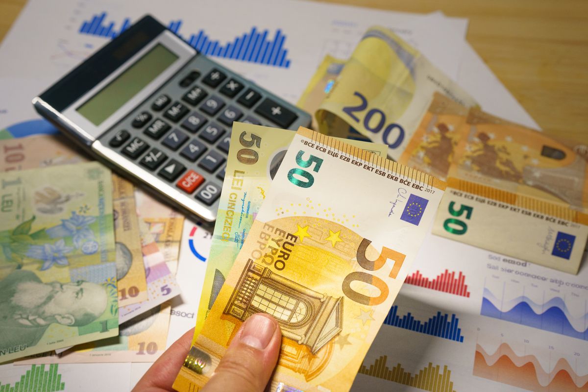 Calculatrice et billets en euros posés sur un bureau, pour choisir entre micro-BIC et régime réel
